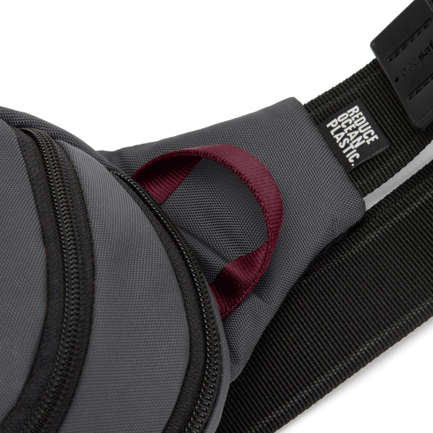 Close-up of the Pacsafe® V Anti-theft Sling Pack's gray strap with maroon loop and "Reduce Ocean Plastic" label.
