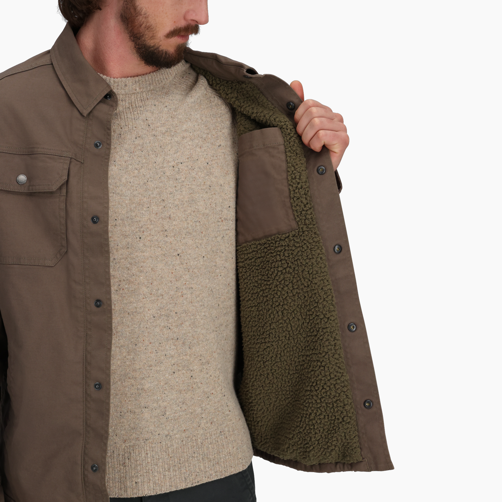 A man shows the olive fleece lining of his Royal Robbins Men's El Cap Canvas Shacket against a white background.