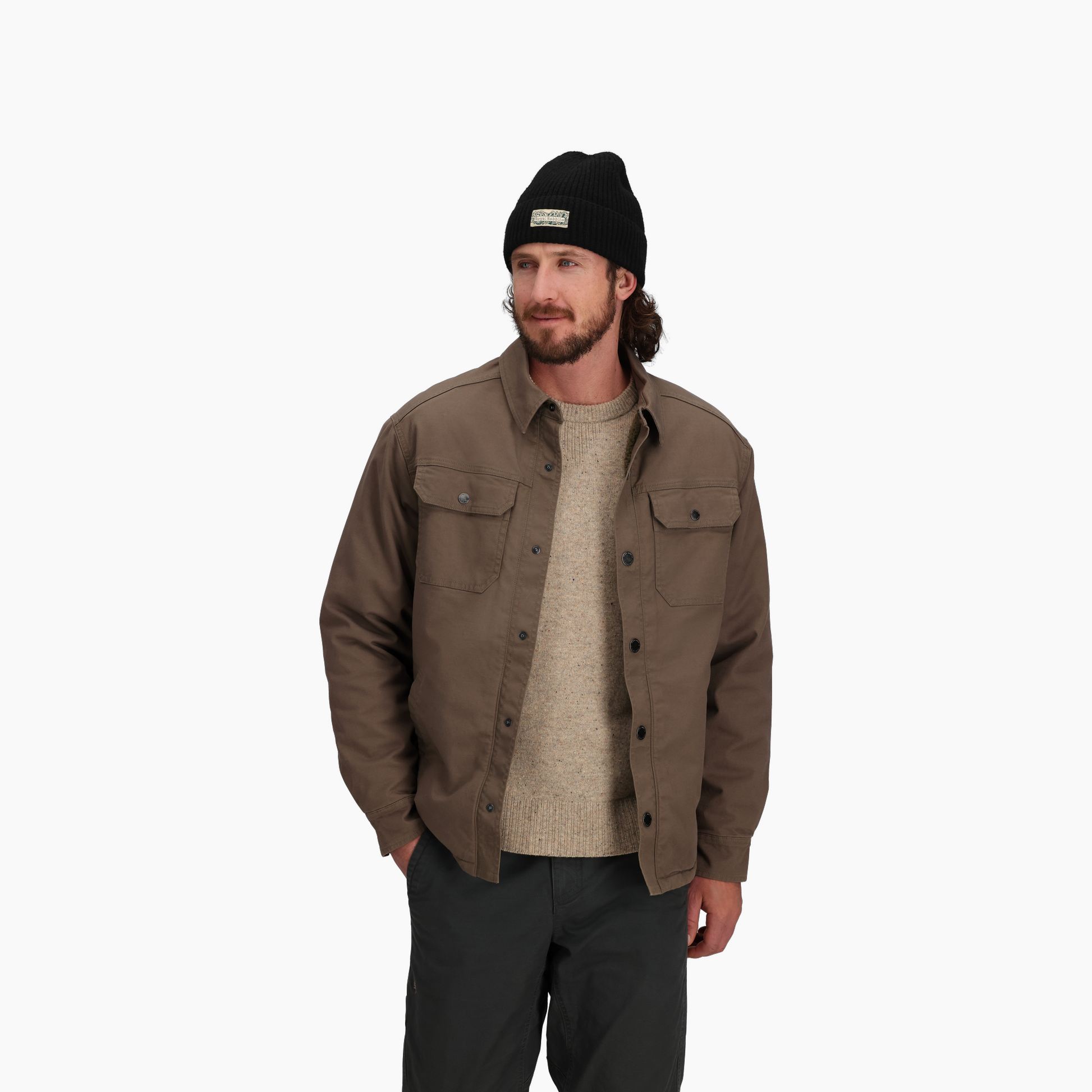 Man wearing Royal Robbins Men's El Cap Canvas Shacket, beige sweater, black pants, and black beanie.