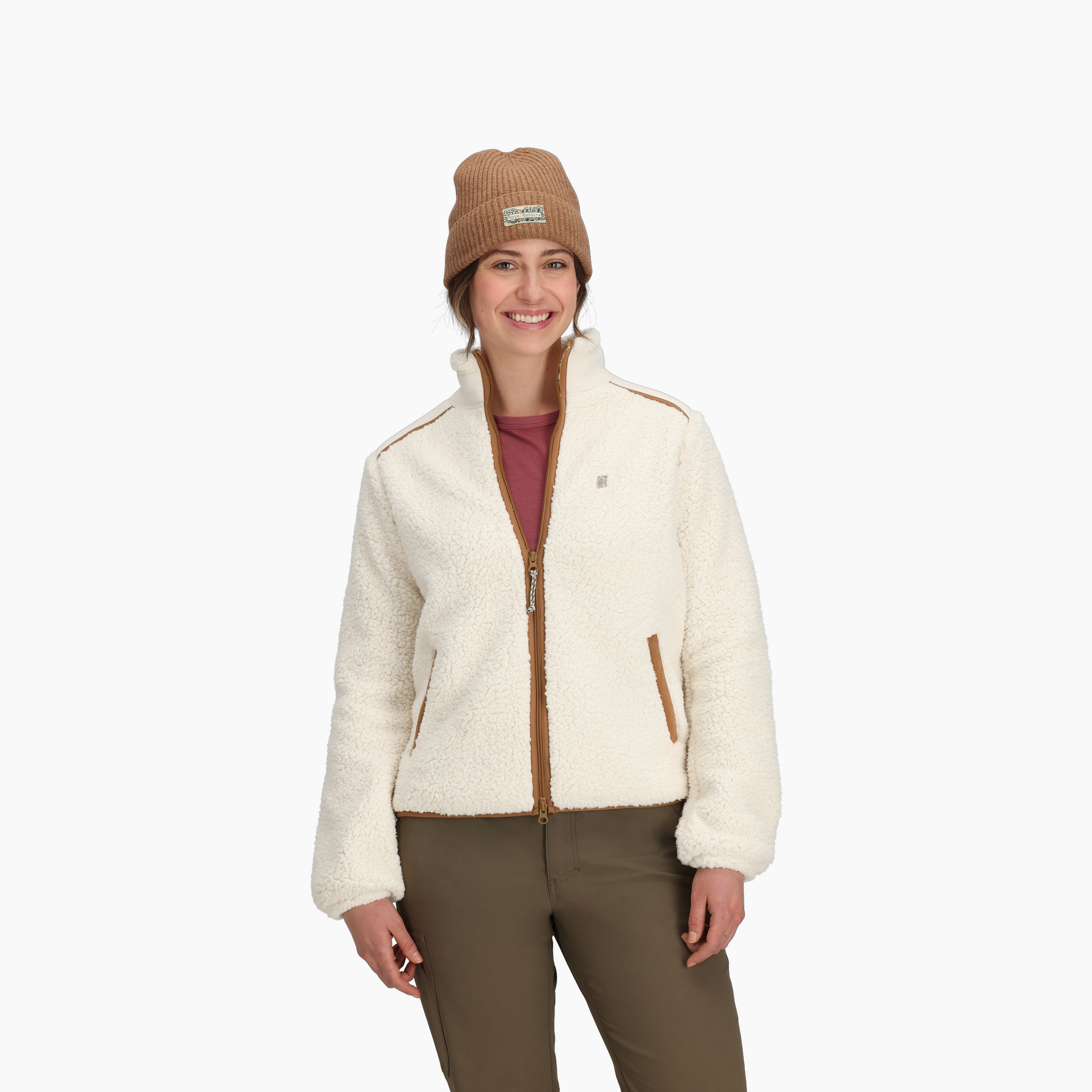 A woman wears the Royal Robbins Women's Palisades Jacket, beige beanie, maroon shirt, and olive pants.