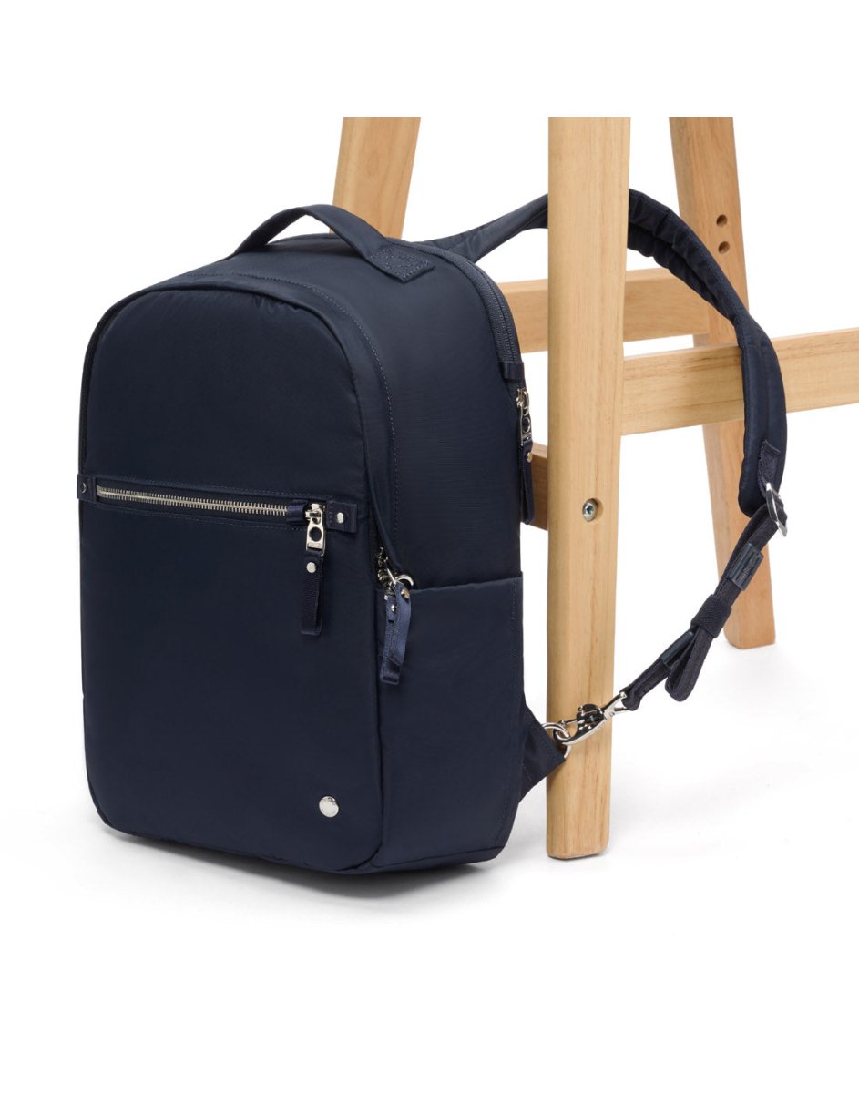 Pacsafe® Navy blue 10L anti-theft backpack with zippers on a wooden chair.