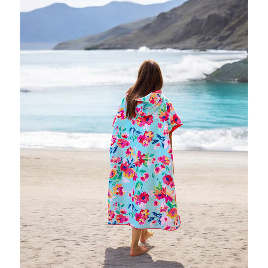 Product Image – A person in a K5 Microfibre Poncho stands on sand, facing the ocean with mountains in the background.