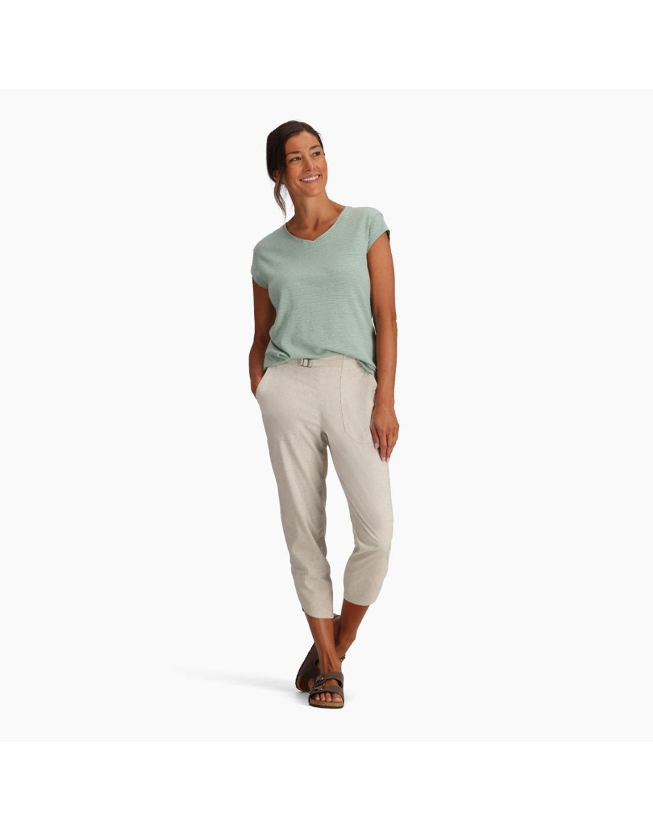 Woman in Royal Robbins Women's Hempline Capri and green top smiles with hands in pockets against a plain background.