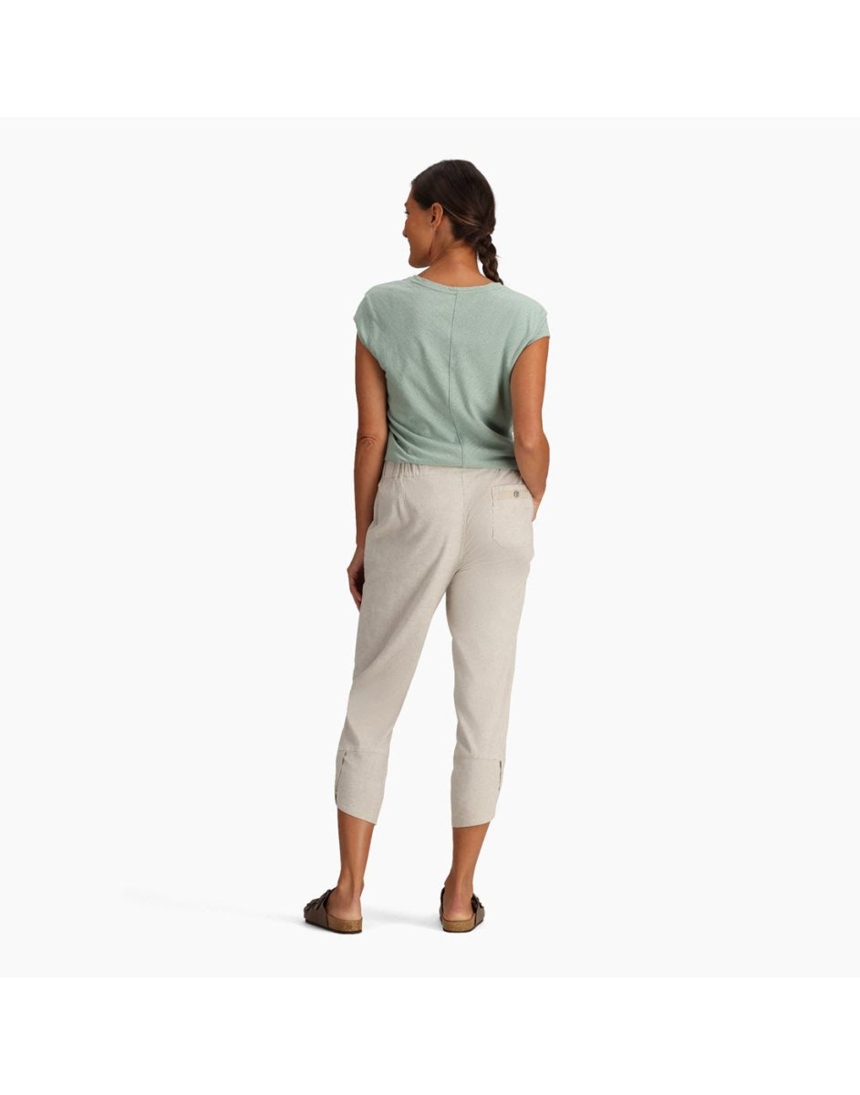 A woman in green and Royal Robbins Hempline Capris stands with her back turned, hands in pockets, hair braided.