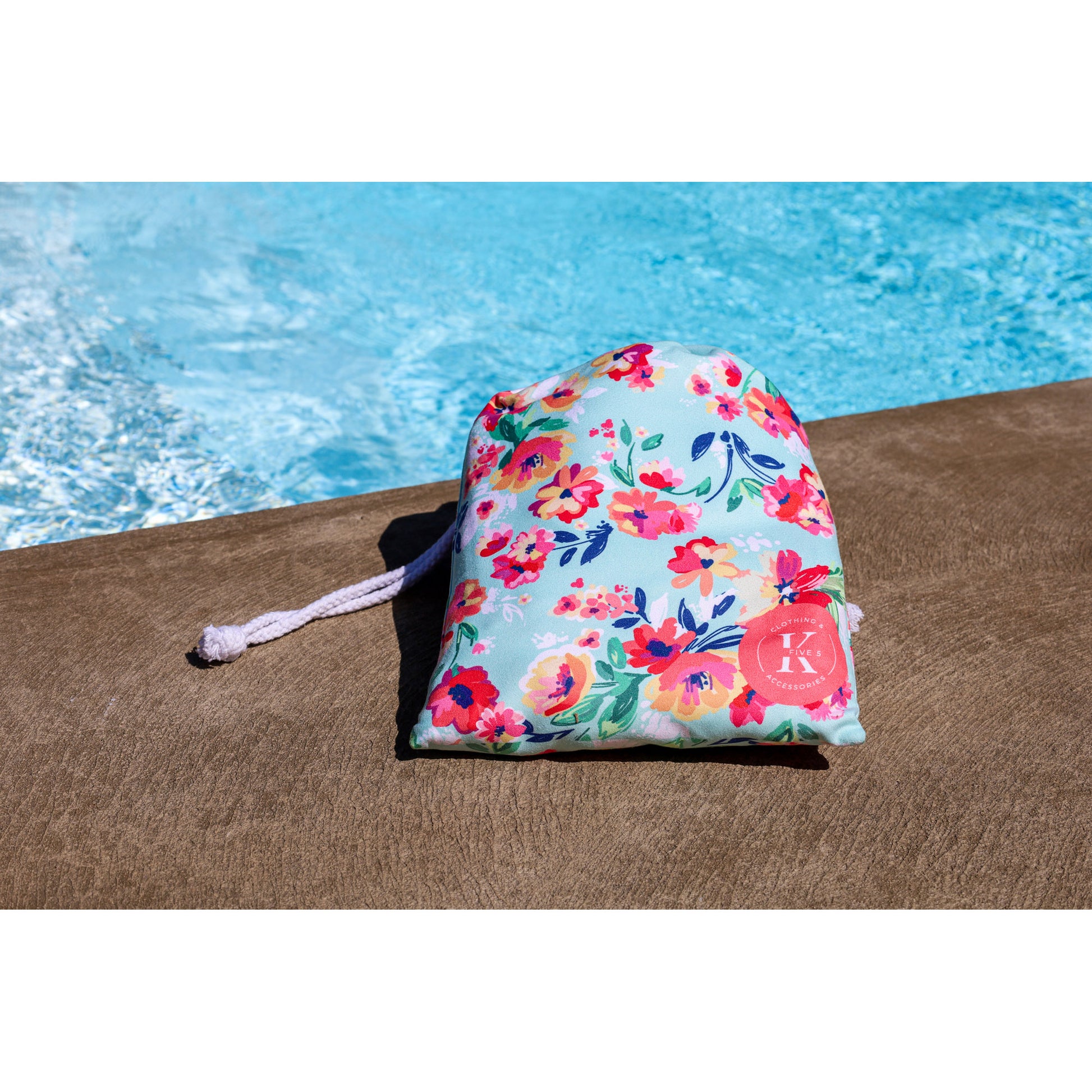 A K5 XXL Microfibre Beach Towel by the pool in a floral bag is ready for your swim.