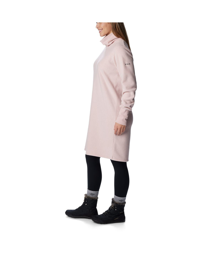 Left side view of a woman wearing a Columbia Women's Boundless Trek™ Fleece Dress in Dusty Pink.  Left sleeves sowing Columbia logo.