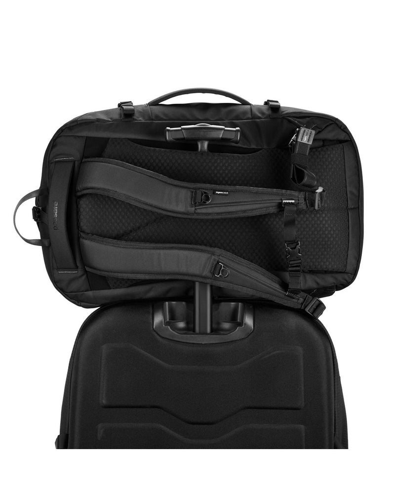 Pacsafe® EXP45 Anti-Theft Carry-on Travel Pack, black, sideways on top of a black suitcase with the handle through the back luggage slip