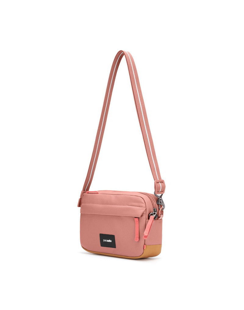 Pacsafe® GO Anti-Theft Crossbody Bag in rose colour side view with Carrysafe® slashguard strap extended.
