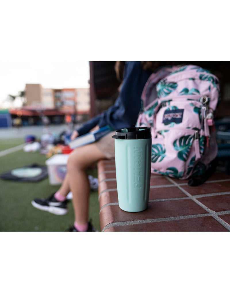 Seafoam colour Pelican 16oz Davyventure Tumbler beside a girl with a backpack