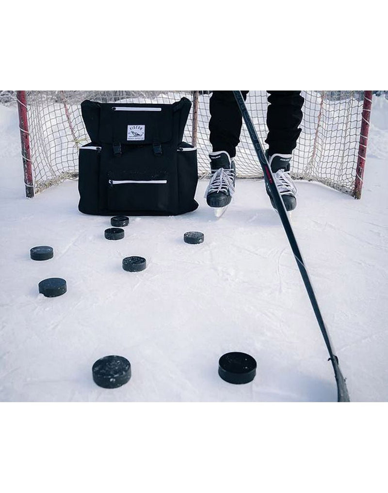 Pigeon Pack on the ice with man's hockey skates  beside in a hockey net with multiple hockey pucks around