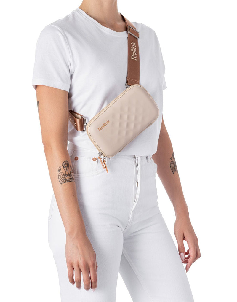 Woman wearing the Rollink Mini Bag Tour in Peach, as a cross-body with strap shortened so bag is at mid-torso height.