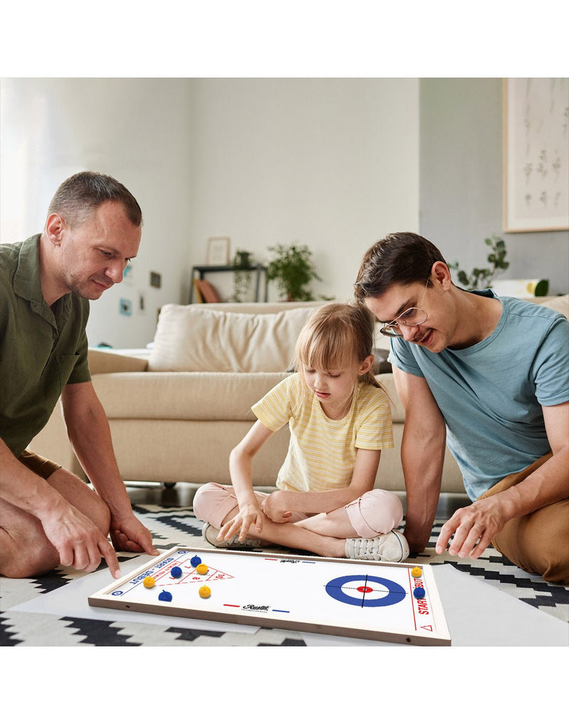 Family playing curling game sitting on floor of living room