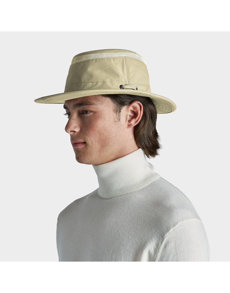 Portrait image of a man wearing white turtleneck sweater and khol colour Tilley LTM5 AIRFLO® Hat, side angled view
