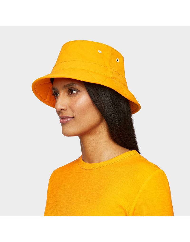 Portrait image of woman wearing Tilley Tofino Bucket Hat in bright orange with matching shirt, side angled view