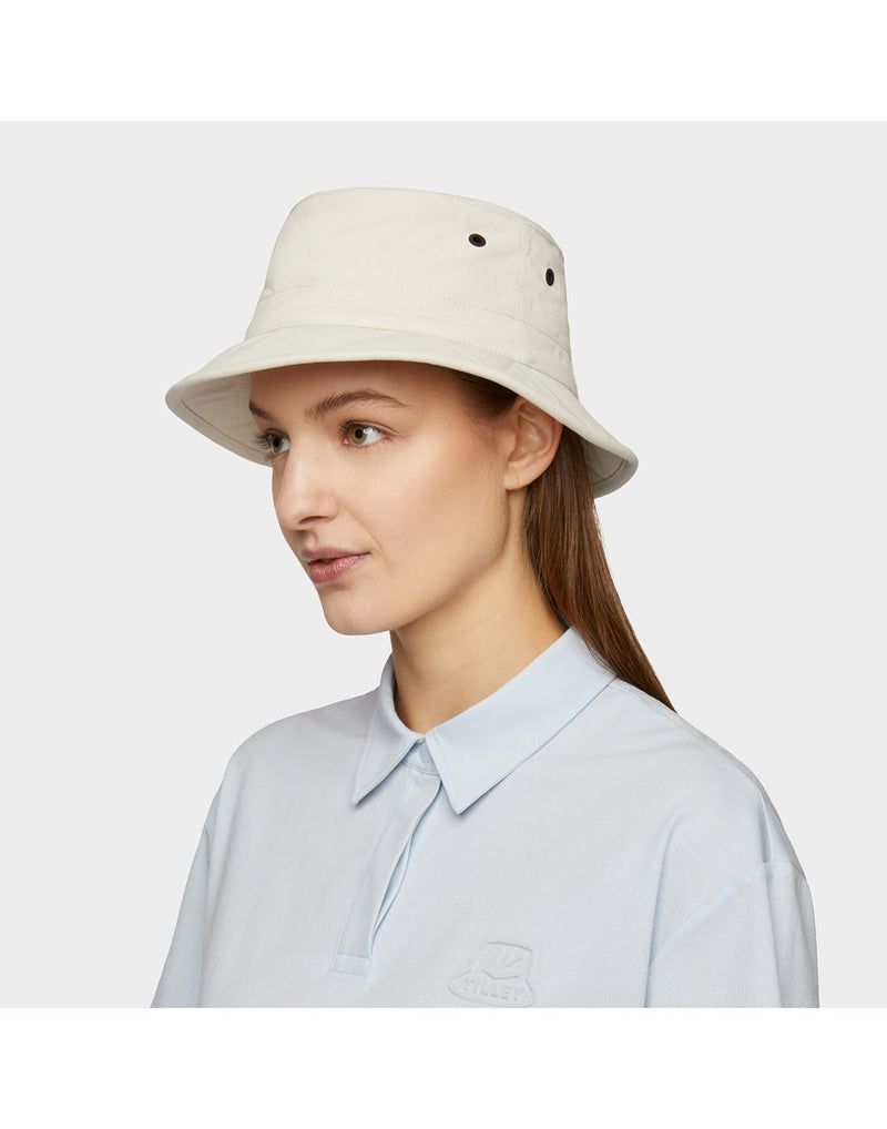 Portrait image of woman wearing light blue button shirt and Tilley Tofino Bucket Hat in stone, side angled view