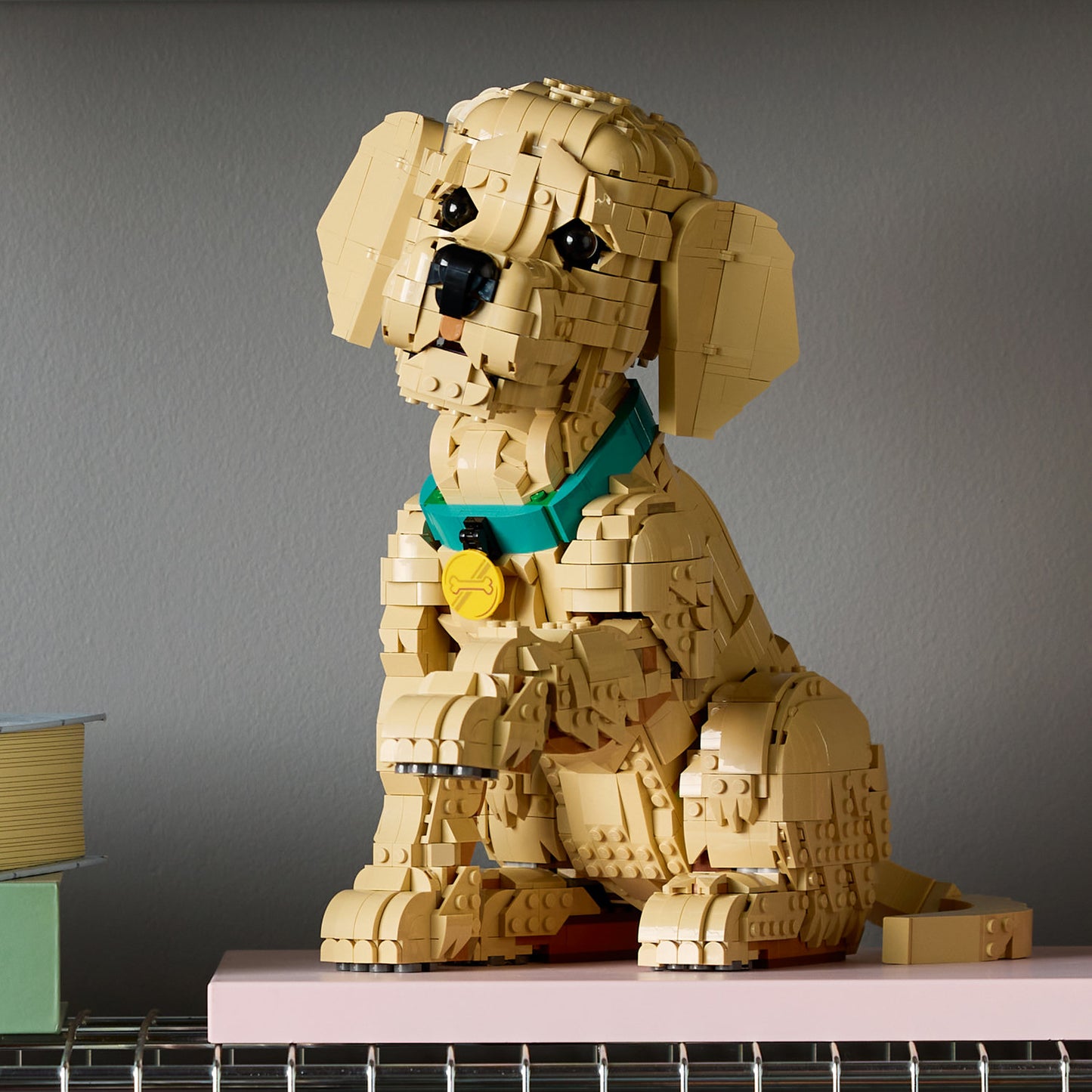 A LEGO® Golden Retriever Puppy with a green collar sits on a pink surface; brand: LEGO, online only.