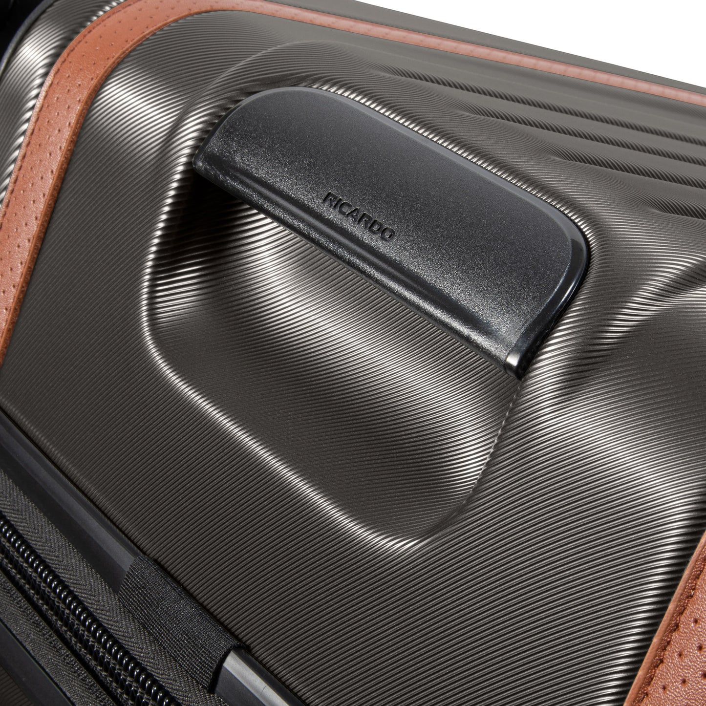 Close-up of Ricardo Beverly Hills black Montecito 2.0 hardside suitcase with textured surface, brown accent, and handle.