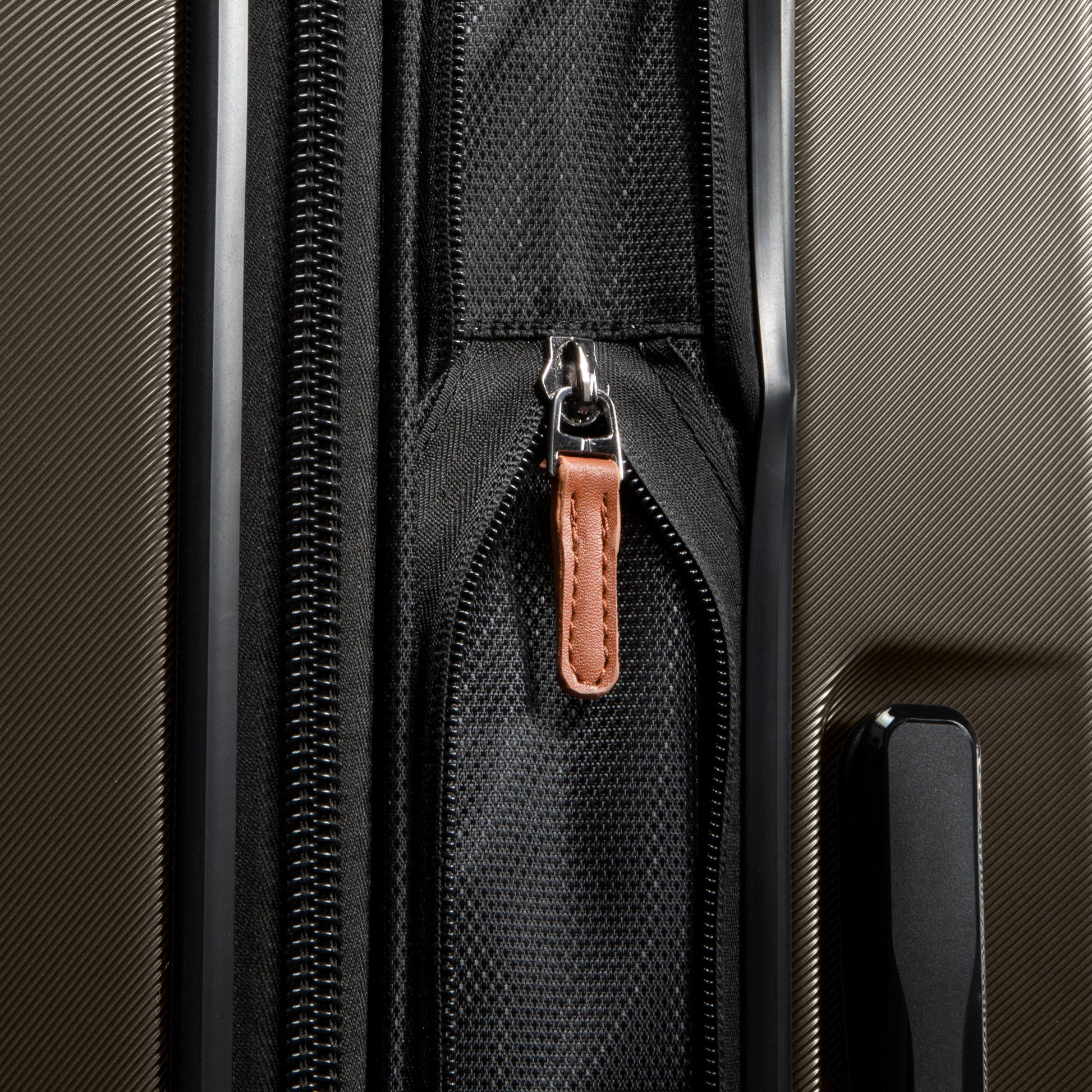 Close-up of the Ricardo Beverly Hills Montecito 2.0 suitcase, featuring expandable storage and a textured black design.