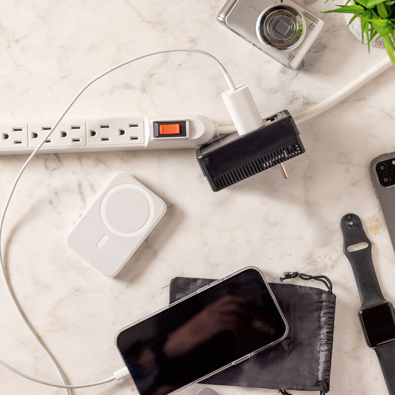 Lifestyle image of Travelon Dual Wattage Converter beside a power bar with a phone charger plugged in