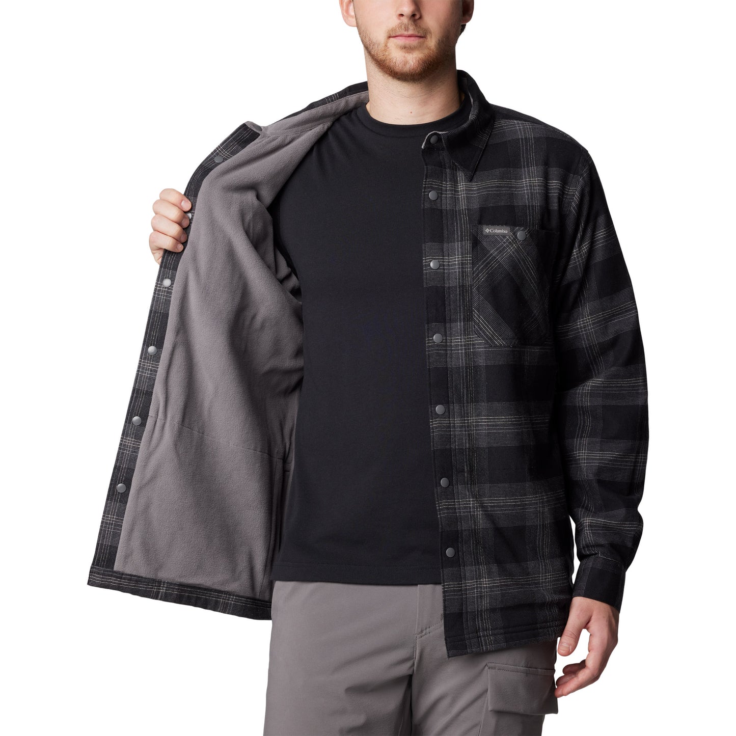 Man wearing Columbia Men's Cornell Woods™ Fleece Lined Shirt Jacket in black buffalo tartan, unbuttoned, holding one side open to show fuzzy lining