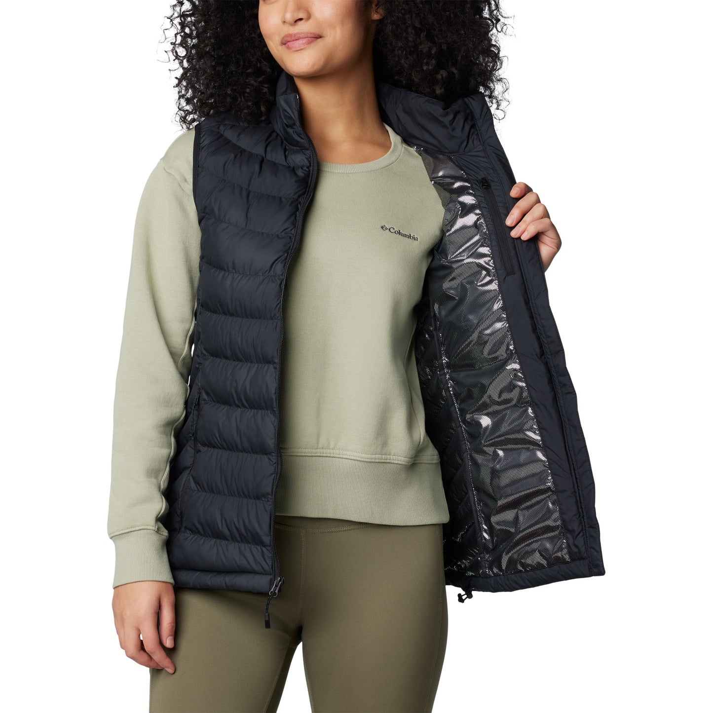 Woman wearing Columbia Women's Powder Lite™ II Vest in black, front view, unzipped, holding one side open to show omni-heat silver lining