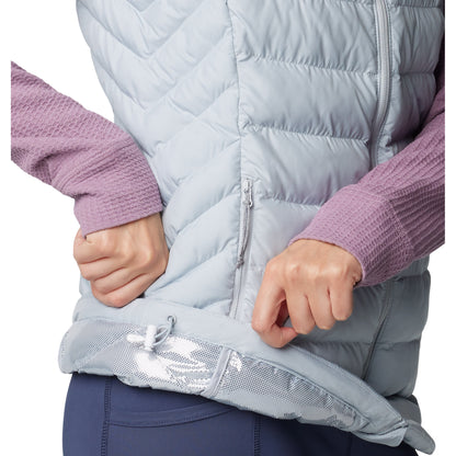 Bottom half of woman wearing Columbia Women's Powder Lite™ II Vest in cirrus grey, side view, holding bottom hem up to show omni-heat silver lining