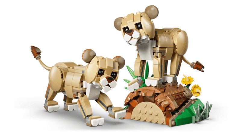 Two LEGO® Wild Animals: Majestic Lion figures by LEGO stand near yellow flowers and a brown mound.