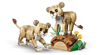 Two LEGO® Wild Animals: Majestic Lion figures by LEGO stand near yellow flowers and a brown mound.
