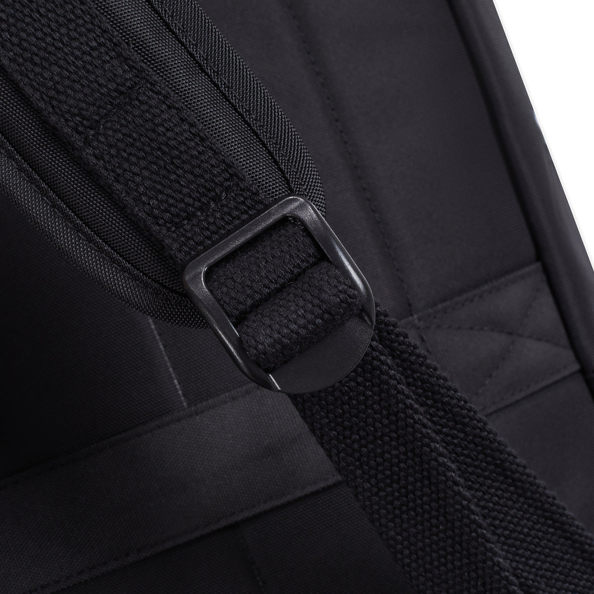 Close-up of Travelon Anti-theft Heritage Backpack’s black strap and buckle, set on black fabric.