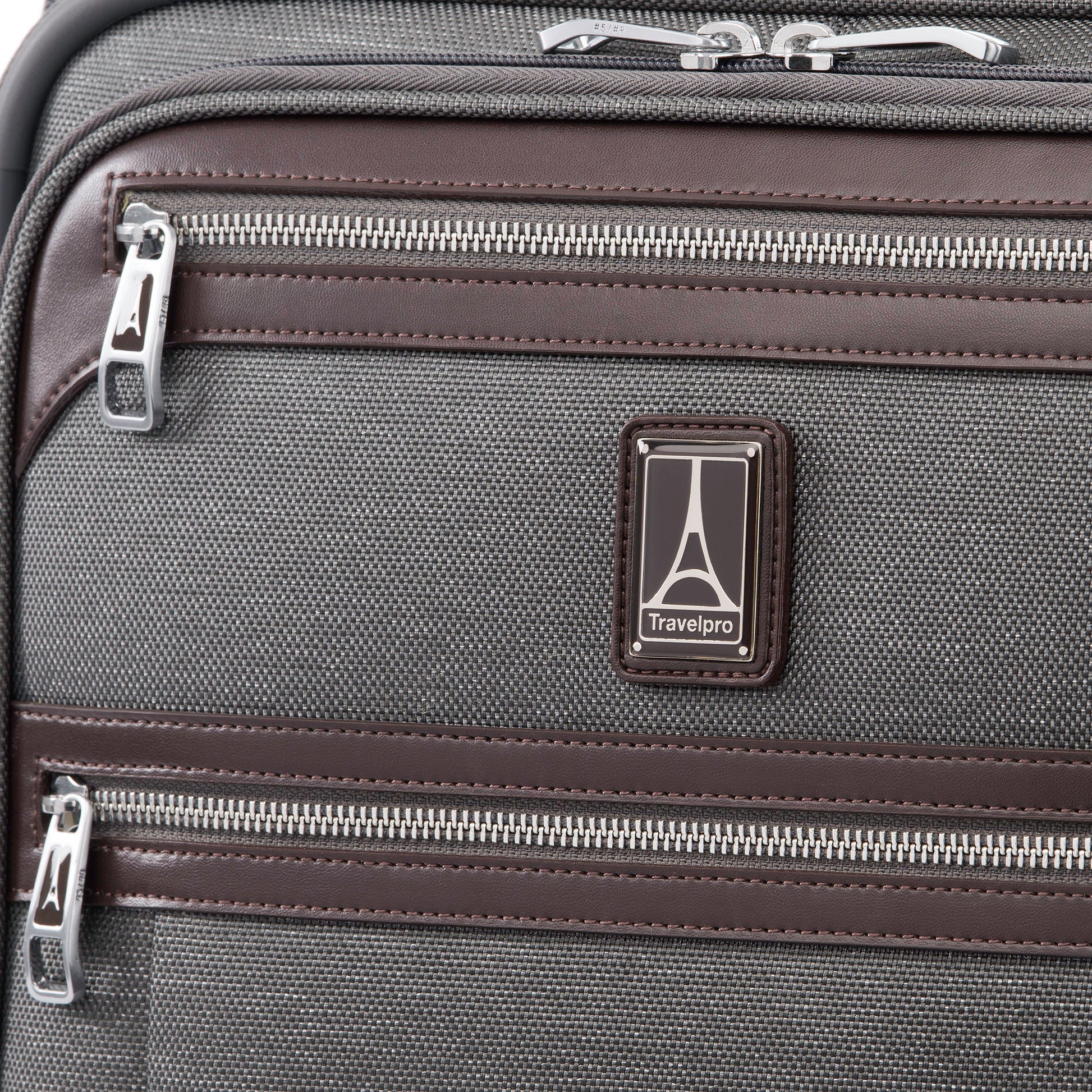 Close up of leather trim around front zipper and Travelpro logo on the vintage grey Travelpro® Platinum® Elite International Expandable Carry-on Spinner