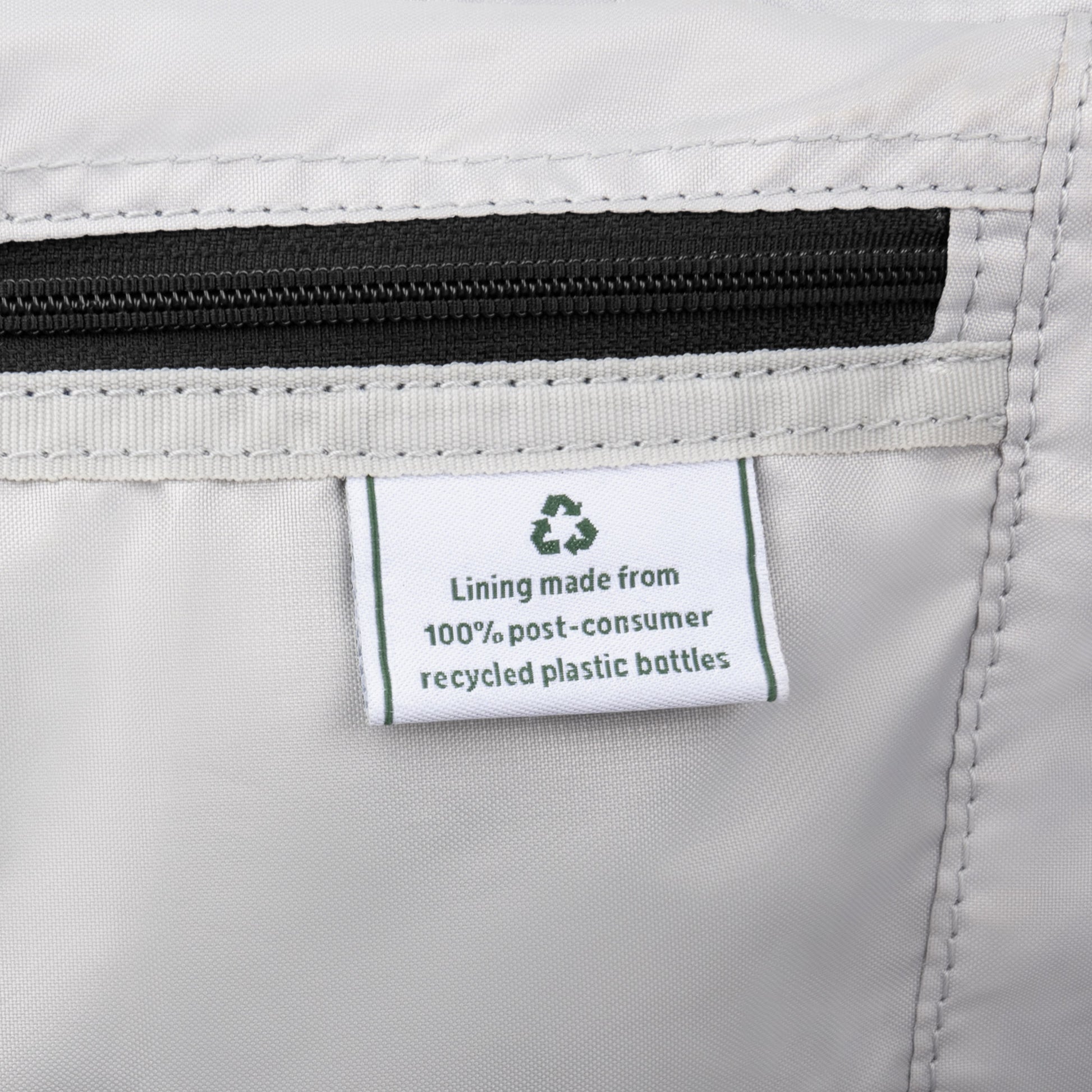 The Travelpro® VersaPack®+ has a white label: "Lining made from 100% post-consumer recycled plastic bottles.