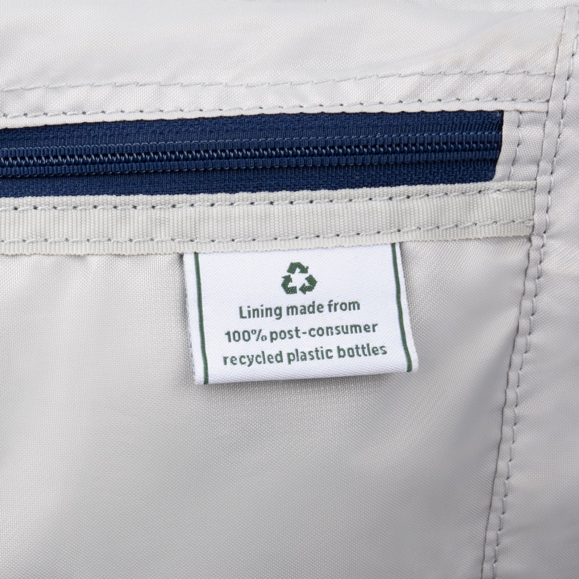 Label on gray fabric of Travelpro® VersaPack®+ Large Spinner: "Lining made from 100% recycled plastic bottles.