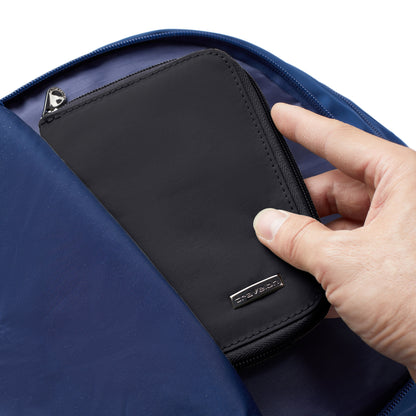 A hand places a Travelon RFID Blocking Zip Passport Wallet into a blue bag.