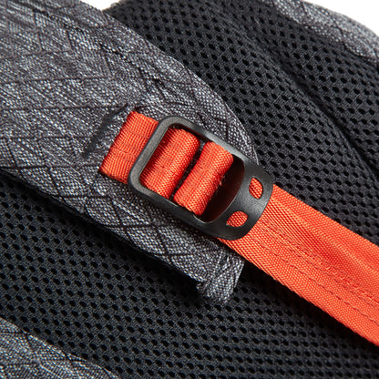 Close-up of a red strap, black buckle, gray RFID-blocking fabric, and mesh on the Travelon 9L Greenlander Backpack.