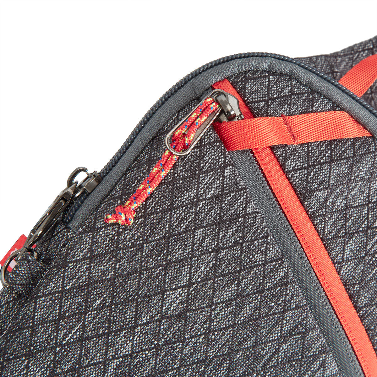 Close-up of Travelon's gray textured sling bag with red/gray zipper pulls, made from recycled materials.