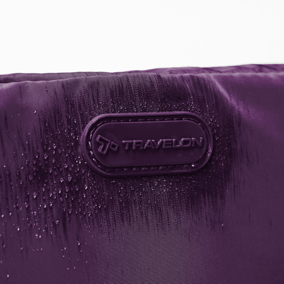 Close up of Travelon logo on front of blackberry Pi Everyway Phone Sling/Belt Bag with water droplets