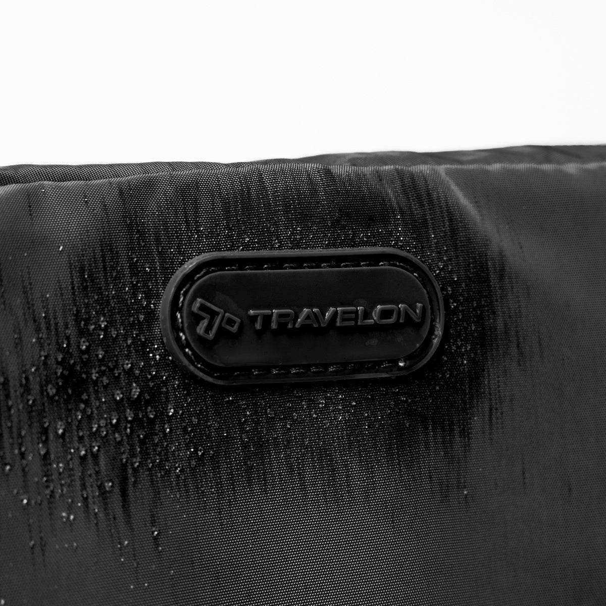 Close up of Travelon logo on black Pi Everyway Phone Sling/Belt Bag, with water droplets