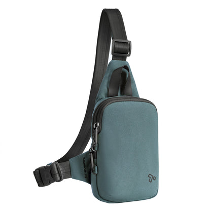 Slate blue Travelon Voyages Anti-Theft Compact Sling with black strap, buckle, front zipper pocket, and Travelon T logo.