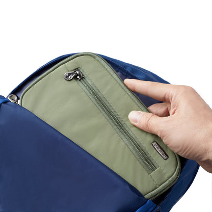 A hand puts a Travelon RFID Blocking Zip Passport Wallet into a blue bag against a white background.