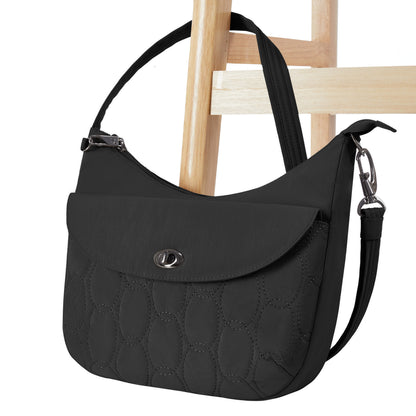 Travelon Runways Anti-theft Medium Crossbody by Travelon with flap closure, shown on a wooden chair.