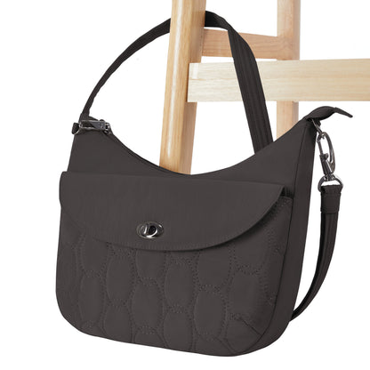 The Travelon Runways Anti-theft Medium Crossbody in black hangs on a wooden chair.