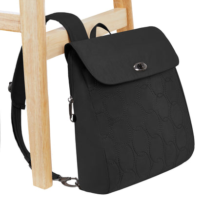 The Travelon Runways Anti-theft Compact Backpack hangs on the back of a light wooden chair.