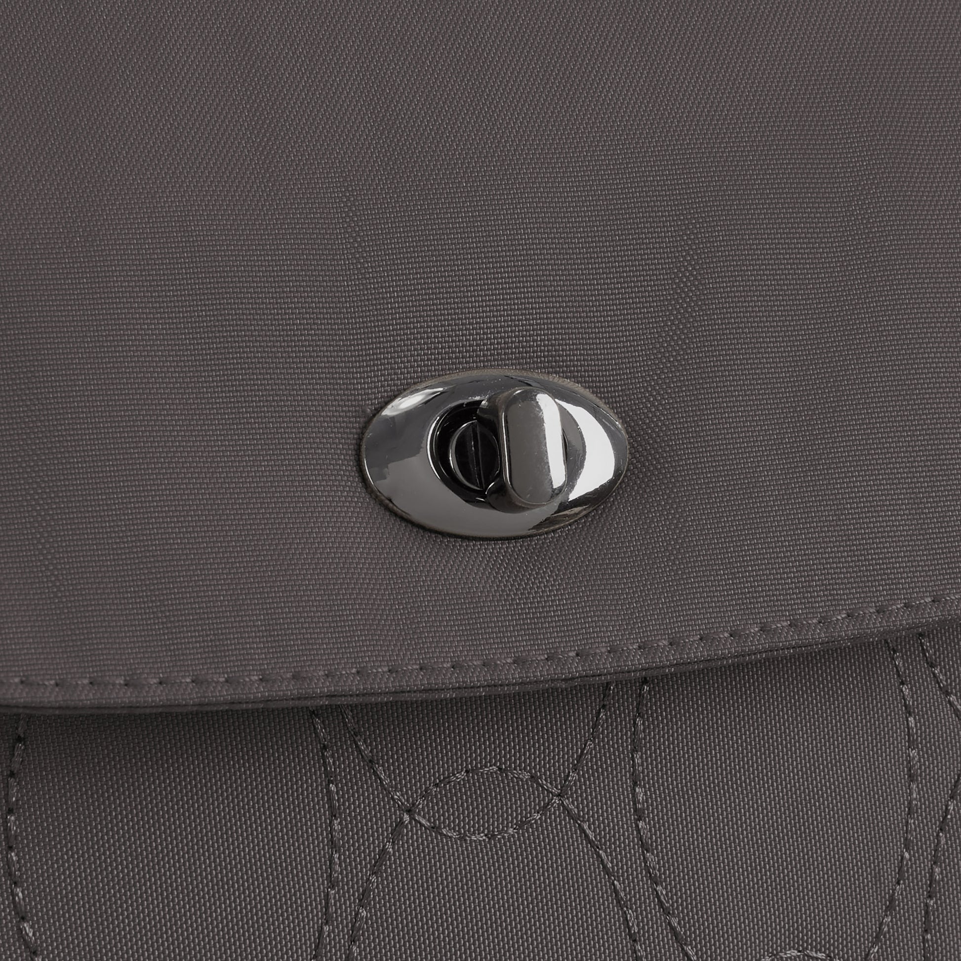 Close-up of the gray Travelon Runways Anti-theft Compact Backpack flap with a silver twist-lock clasp.