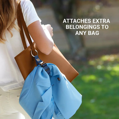 Person carrying a tan tote with a blue jacket attached using the Go Travel Everyday Carry Clip by Go Travel.