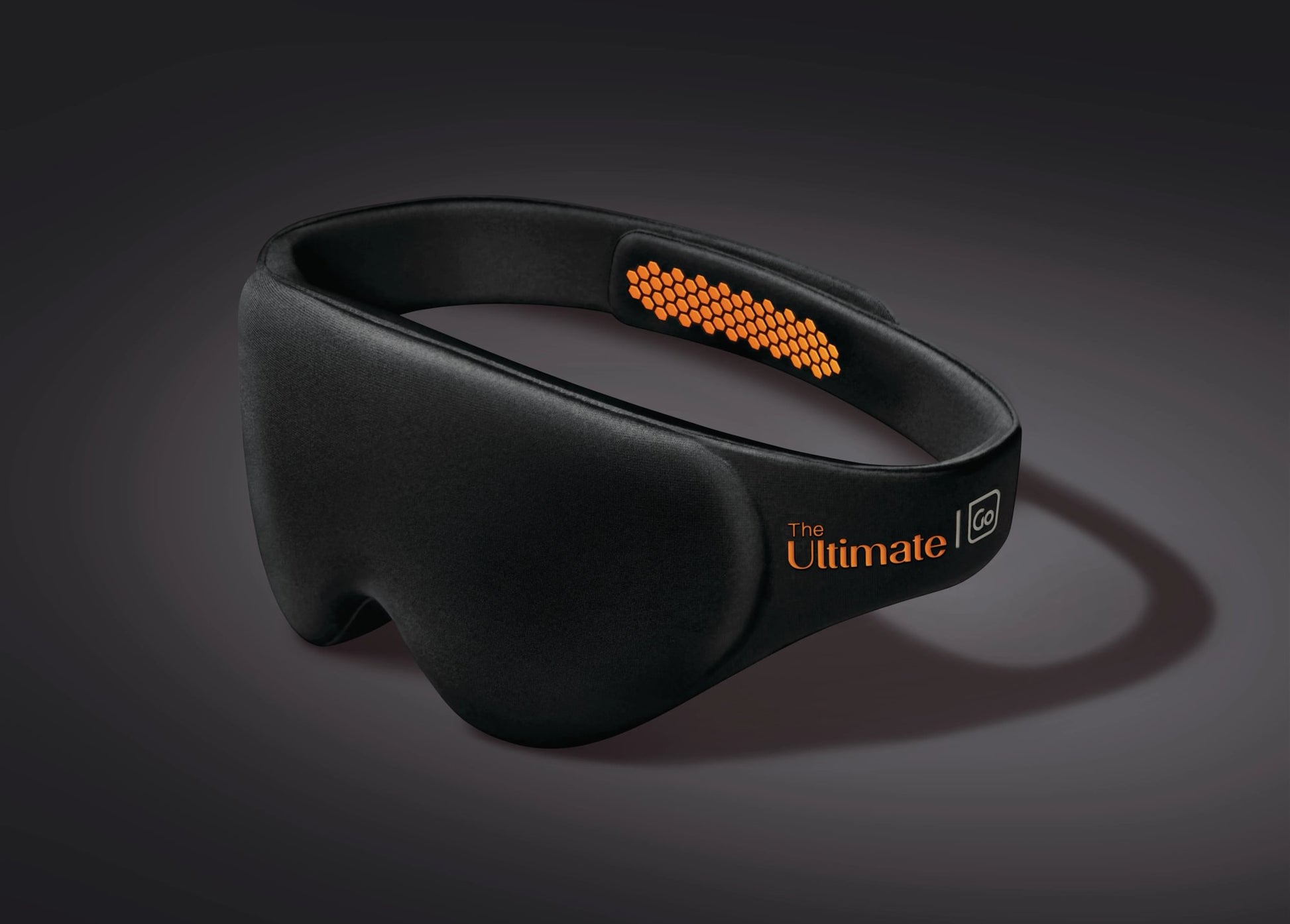 The Go Travel The Ultimate Eye Mask is black with orange hexagonal pads and "The Ultimate" on the headband.