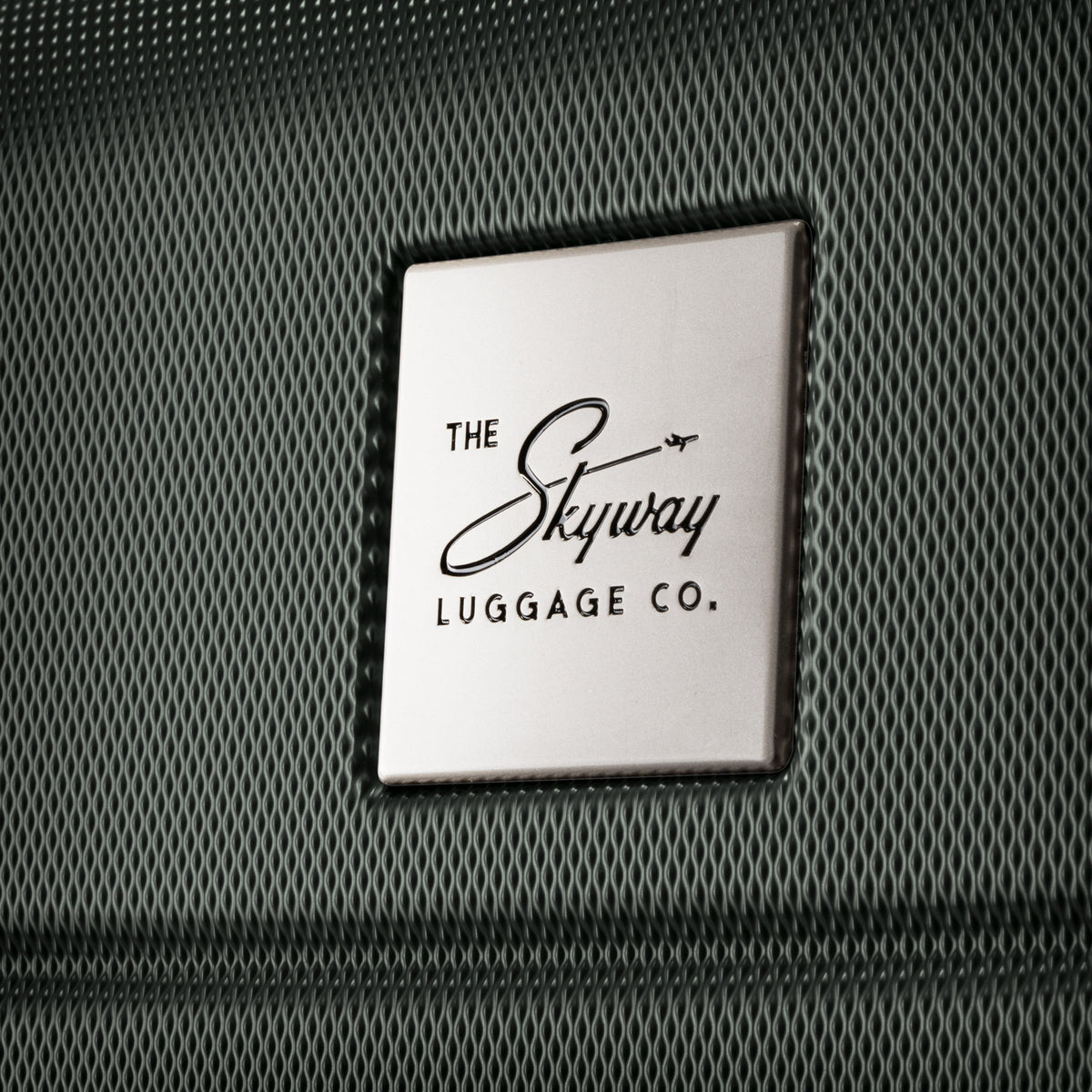 Close-up of Skyway logo plate on a Skyway Epic 2.0 Hardside Medium Check-in Spinner surface.