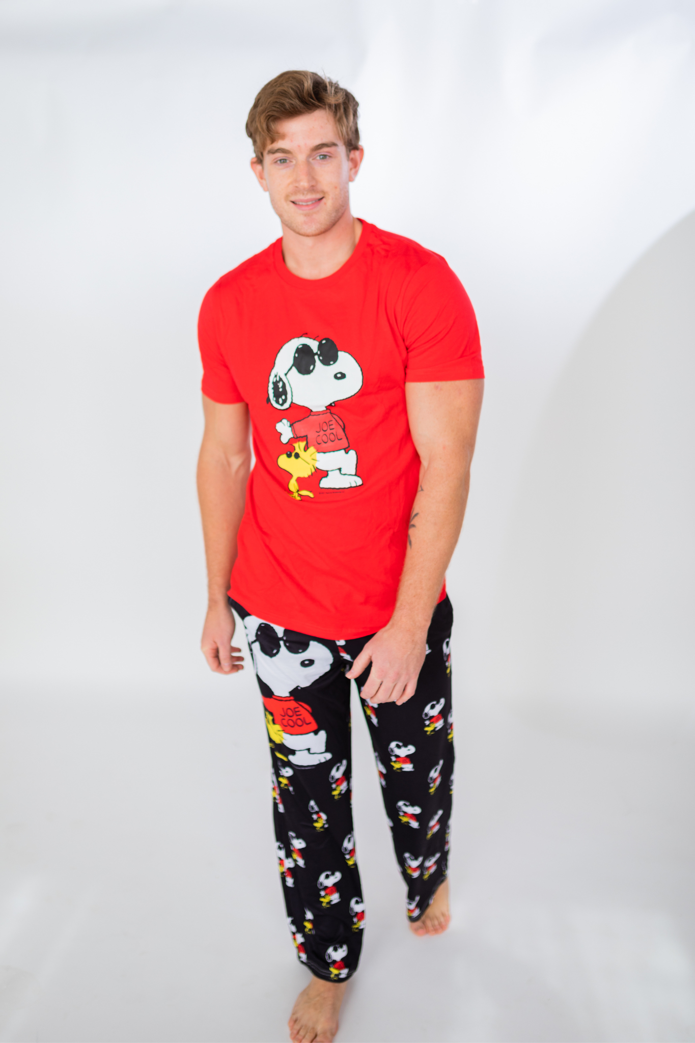 Man wearing Brief Insanity Lounge Pants - Peanuts Snoopy Joe Cool, barefoot against a white background.