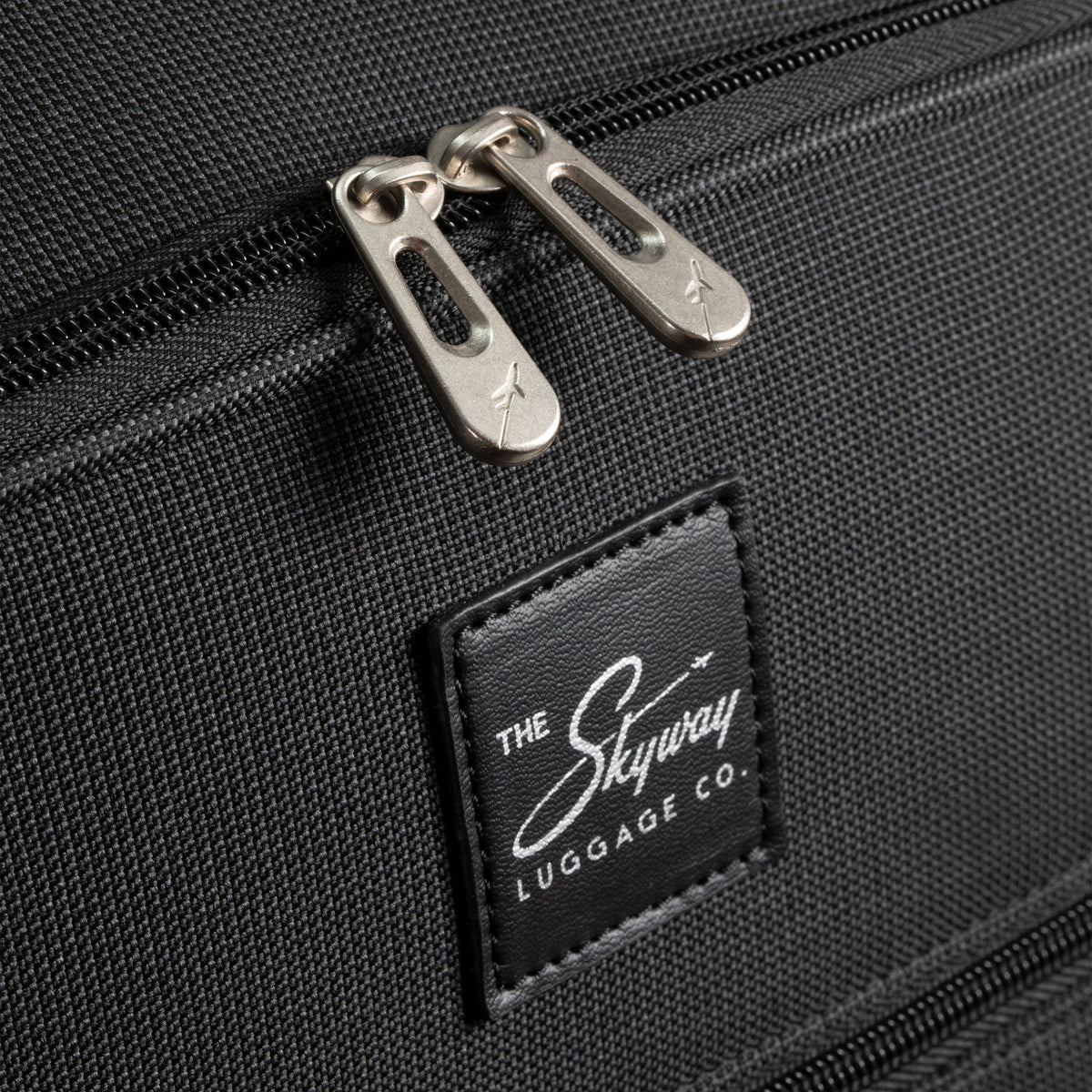 Black zipper pulls and a Skyway branded patch on a Skyway Flair 2.0 3-Piece Luggage Set.