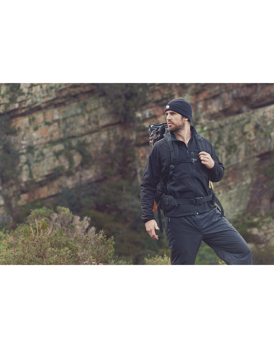 Lifestyle image of man in the outdoors with a backpack, wearing the Icetrax Beanie with Light