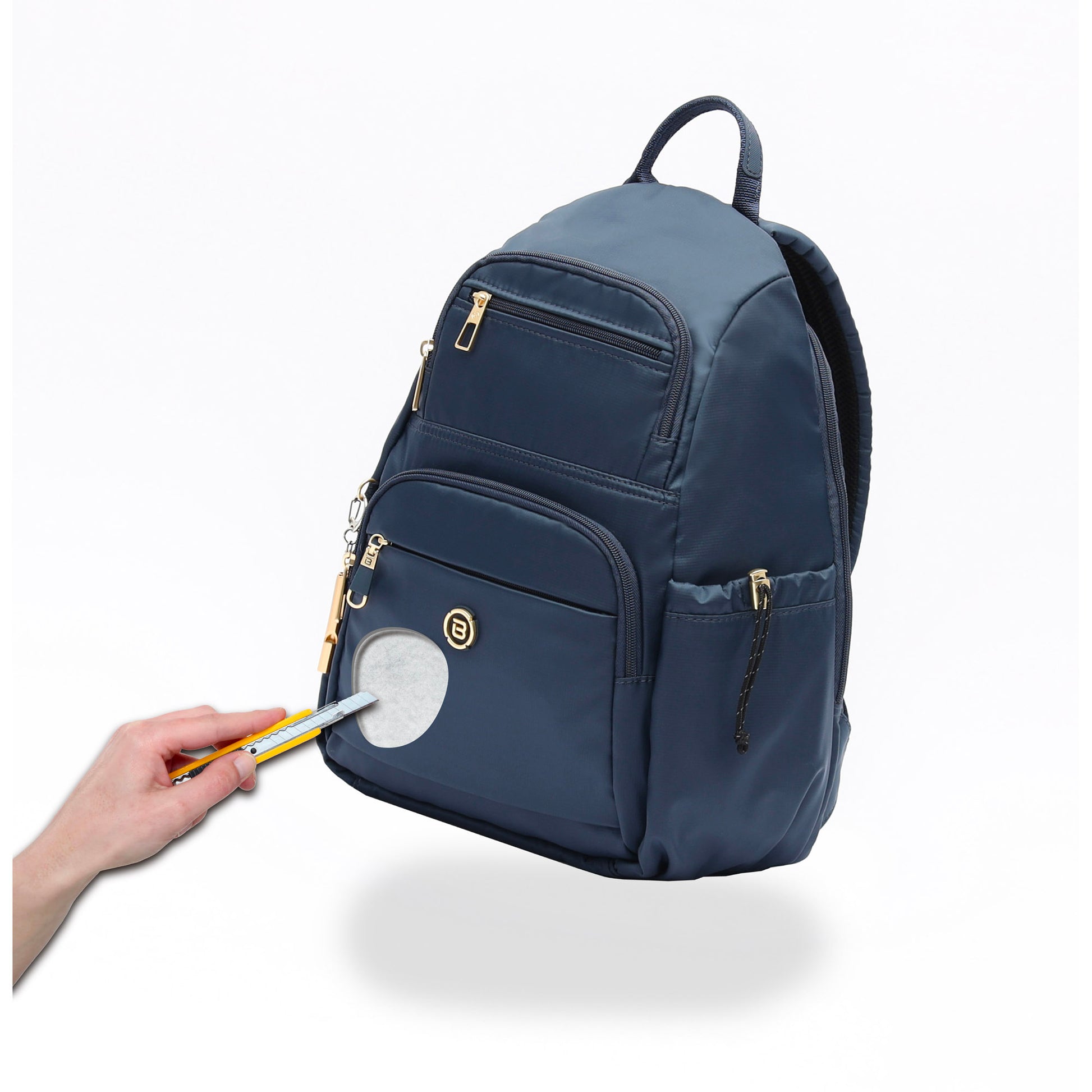 A hand with a pencil points at the circular patch on the Beside-U Aileen R1 Backpack.